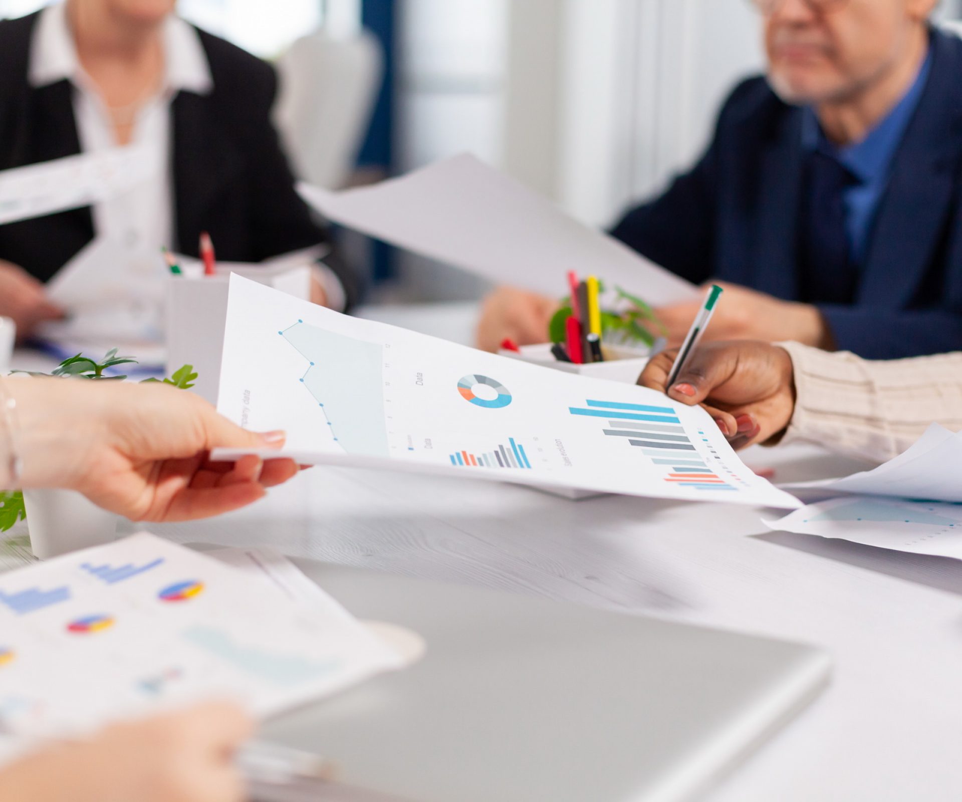 Close up of diverse startup company colleagues meeting in professional workplace, brifing and sharing ideas over financial strategy. Colleagues working in office at conference table in startup management company.